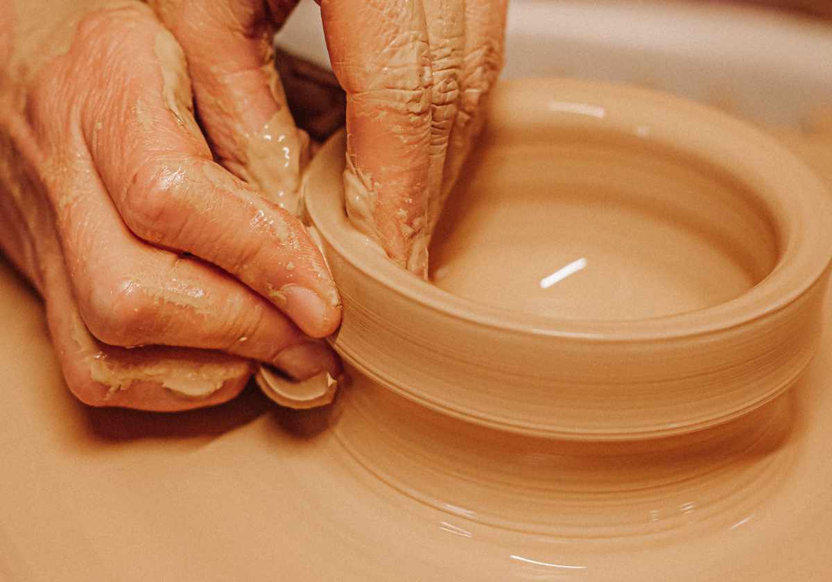 Claudia Entner Keramikprodukte: Hände, die gerade auf der Töpferscheibe eine Wandung hochziehen
